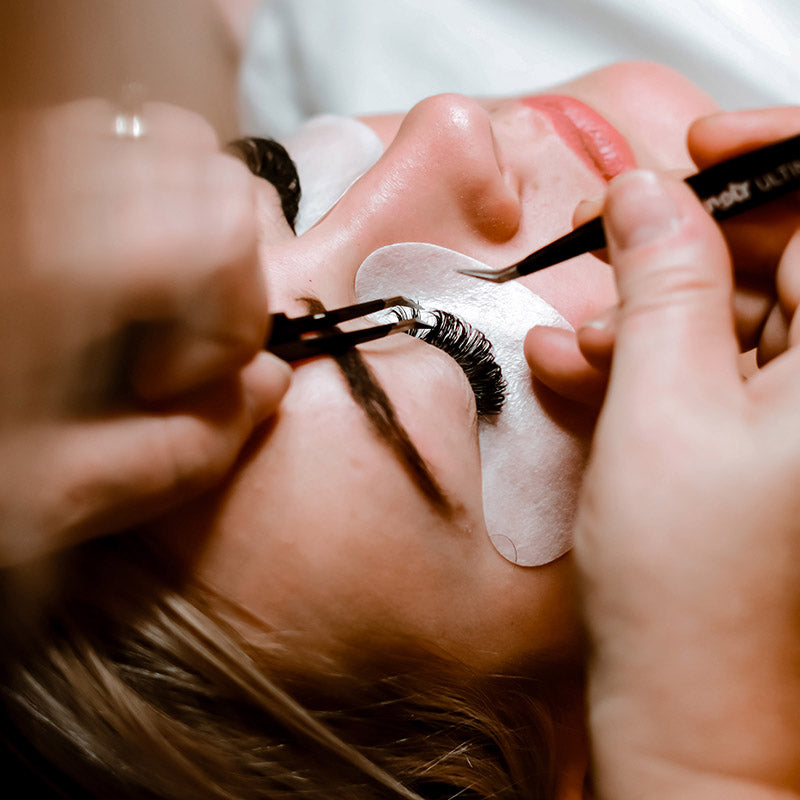 Woman receiving lash extensions at Shine, an organic spray tanning location with specialized spa treatments.