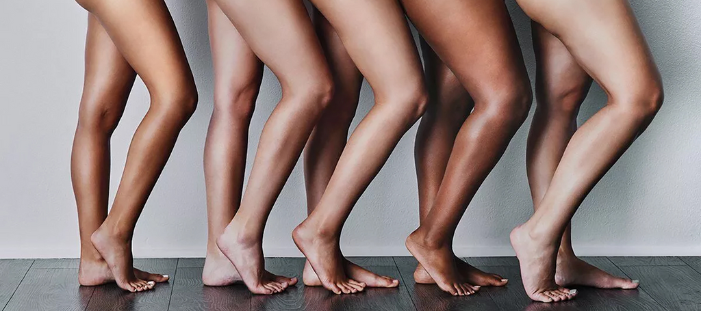 Five pairs of sunless tan legs, ranging from light to dark complexions.